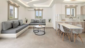 A modern living room with a sofa, a coffee table, and a dining area with chairs and a table. - Peacefull Santorini Luxury Villa-Private Jacuzzi & Iconic Windmill Views (Thira - Santorini)