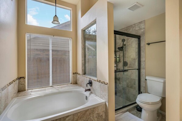 Une salle de bain avec une baignoire, des toilettes et une douche à parois en verre.