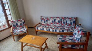 A room with a sofa set, two armchairs, and a coffee table.