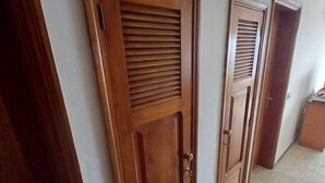 A hallway with two wooden doors, one with a window and the other with a vent.