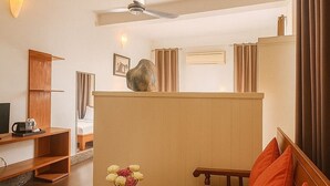 Uma sala de estar moderna com uma mesa de centro de madeira, um sofá bege com almofadas laranja, uma televisão e um ventilador de teto.