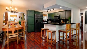 A modern kitchen with a central island, wooden dining table, and bar stools. - •Hacienda de Amor• Heated pool - Hot Tub - Firepit (Wilton Manors)
