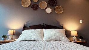A bedroom with a large bed, two bedside tables with lamps, and a wall decorated with circular woven items. - Beautiful apartment with incredible view. Super spacious, comfortable and full of light (Cochabamba)