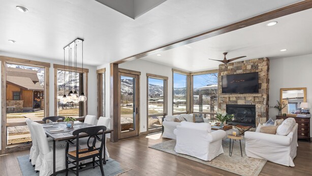 A spacious living area with a fireplace, white furniture, and large windows offering mountain views.