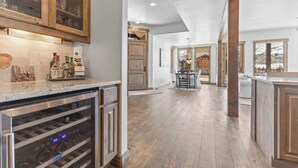 A kitchen with wooden cabinets, a wine cooler, and a dining area with a table and chairs.