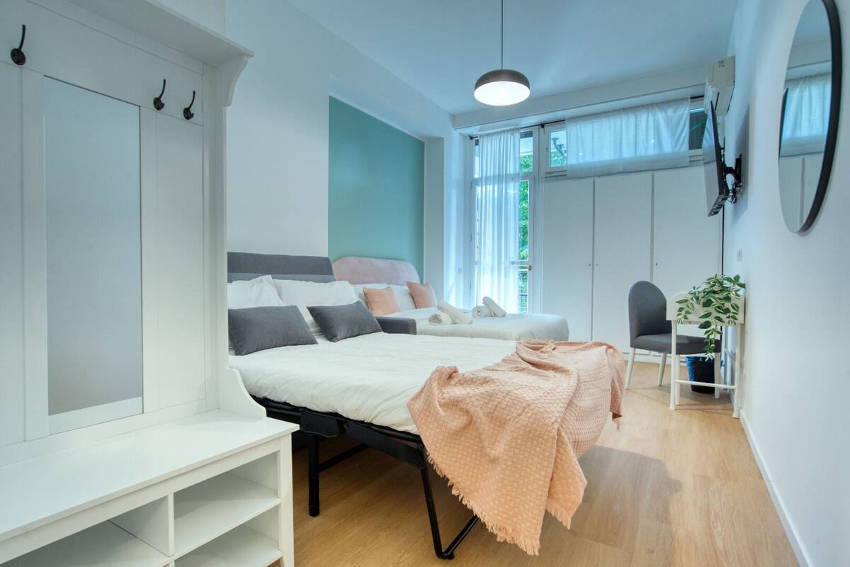 A modern bedroom with a bed, a chair, a desk, and a wardrobe.