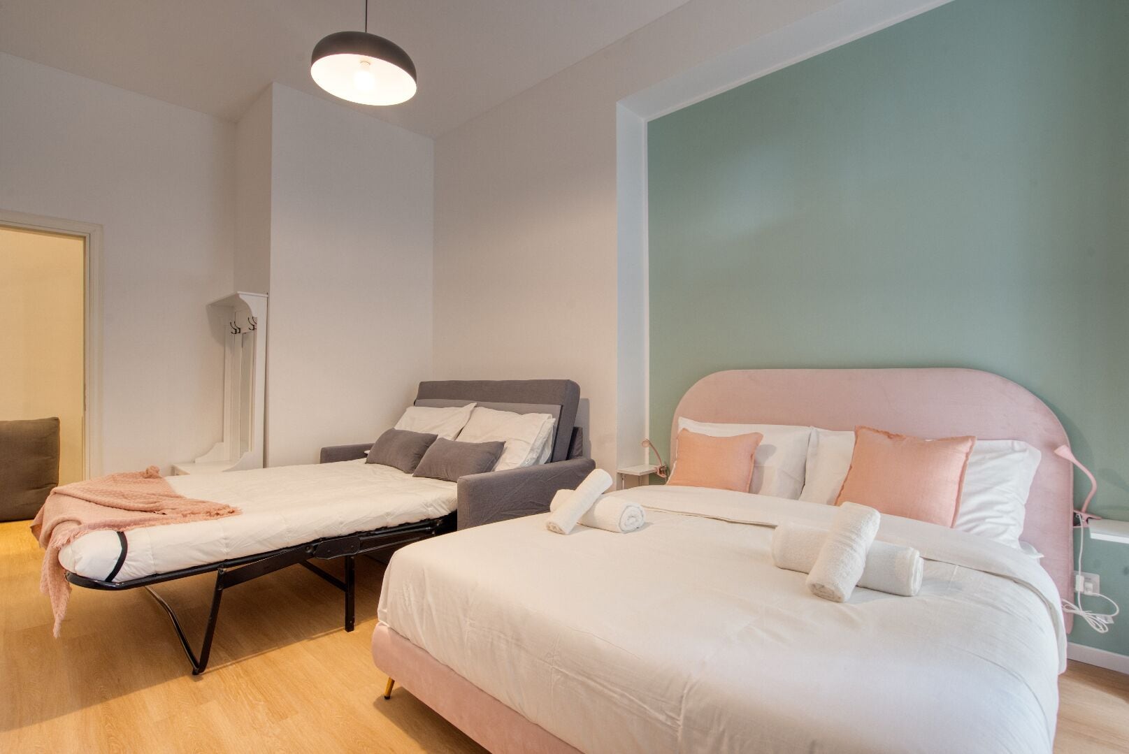 A bedroom with a bed, a chair, and a bedside table.