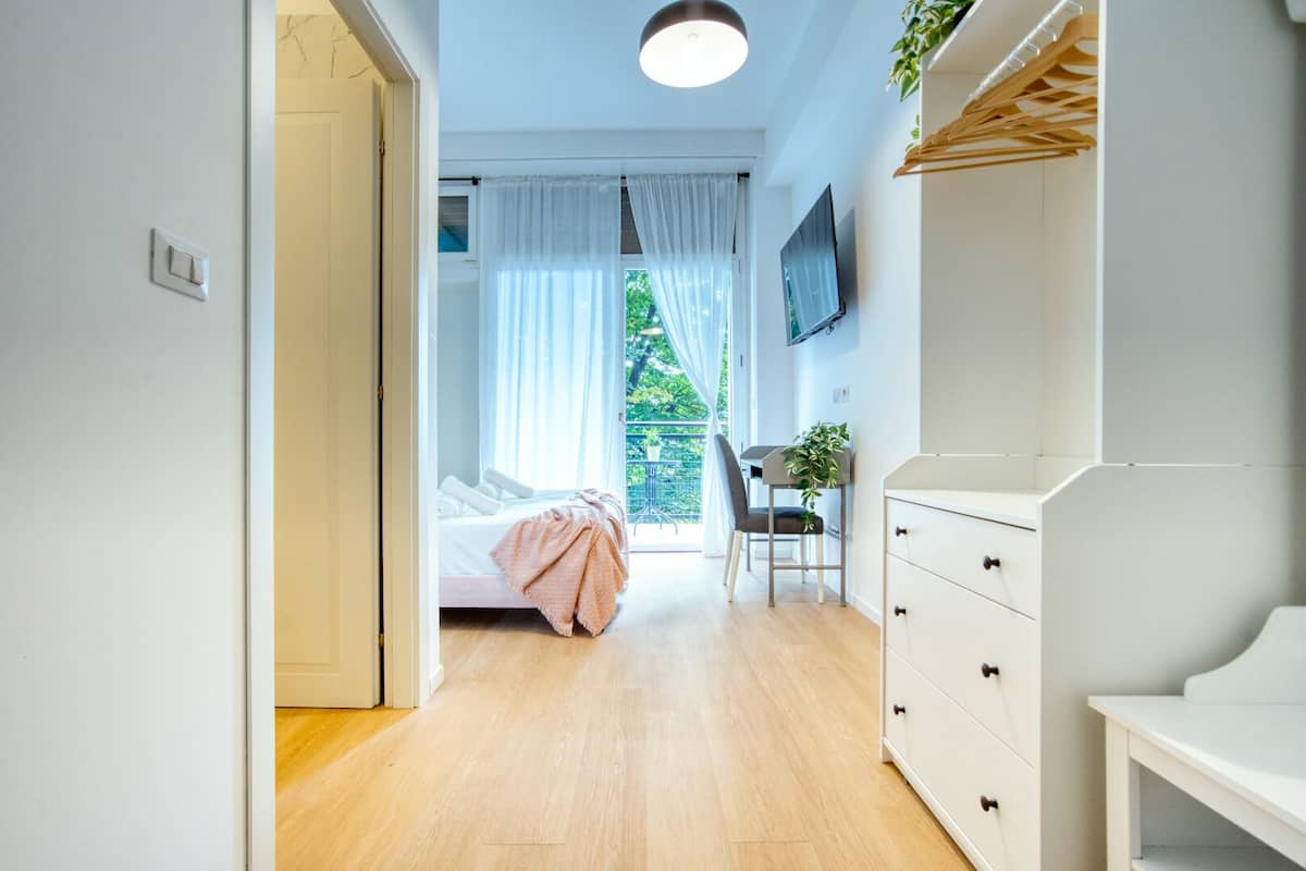A modern bedroom with a bed, a desk, and a TV.