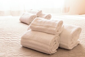 Un lit recouvert d’une courtepointe et agrémenté de serviettes blanches soigneusement pliées.