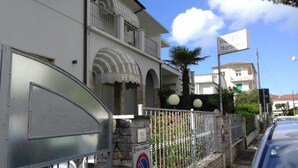 Un hotel llamado "HOTEL Moranna" con fachada blanca, balcones y una entrada protegida por una reja.