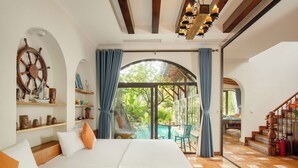 Un dormitorio con una cama grande, un adorno de timón y vista a un jardín a través de una puerta de cristal.