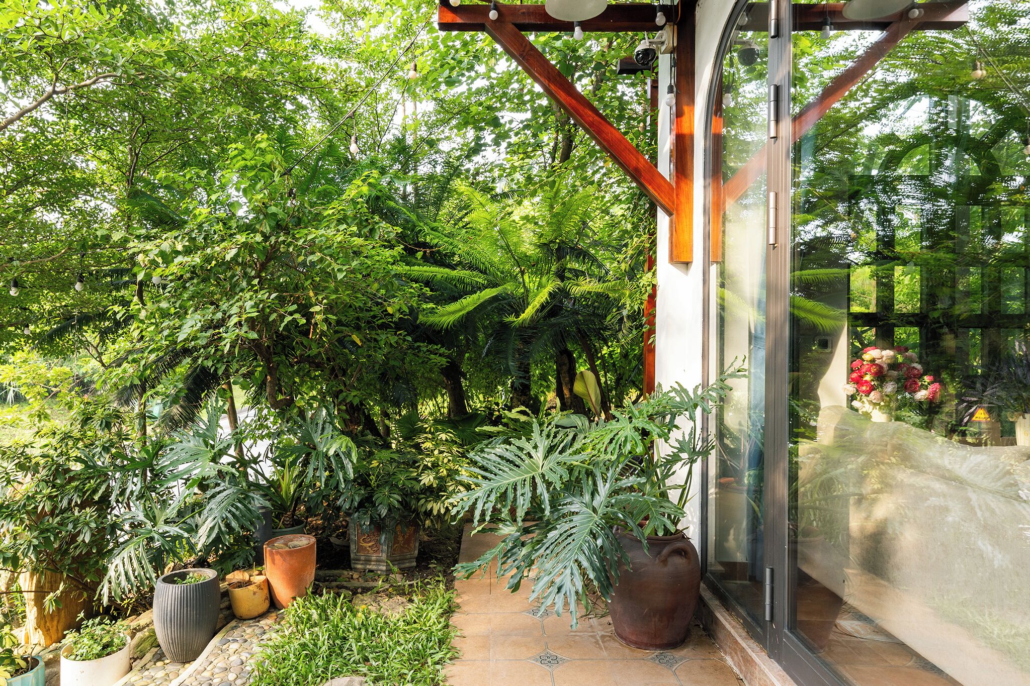 A lush garden with various potted plants and a glass door leading to a patio area.