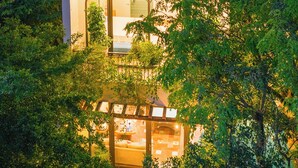 Una casa moderna con fachada de vidrio, rodeada de exuberante vegetación.
