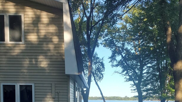 Una casa con terraza de madera que da a un lago.