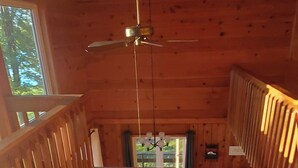 Interior de una cabaña de madera con comedor, sofá y escalera.