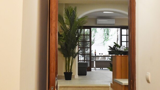 A hallway leading to a dining area with a staircase, a potted plant, and a view of the outdoors. - Acropolis Gate (Athina)