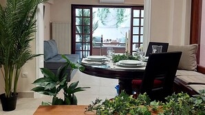 A dining area with a round table set for four, a sofa, and a large potted plant. - Acropolis Gate (Athina)
