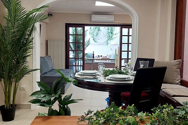 A dining area with a round table set for four, a sofa, and a large potted plant. - Acropolis Gate (Athina)
