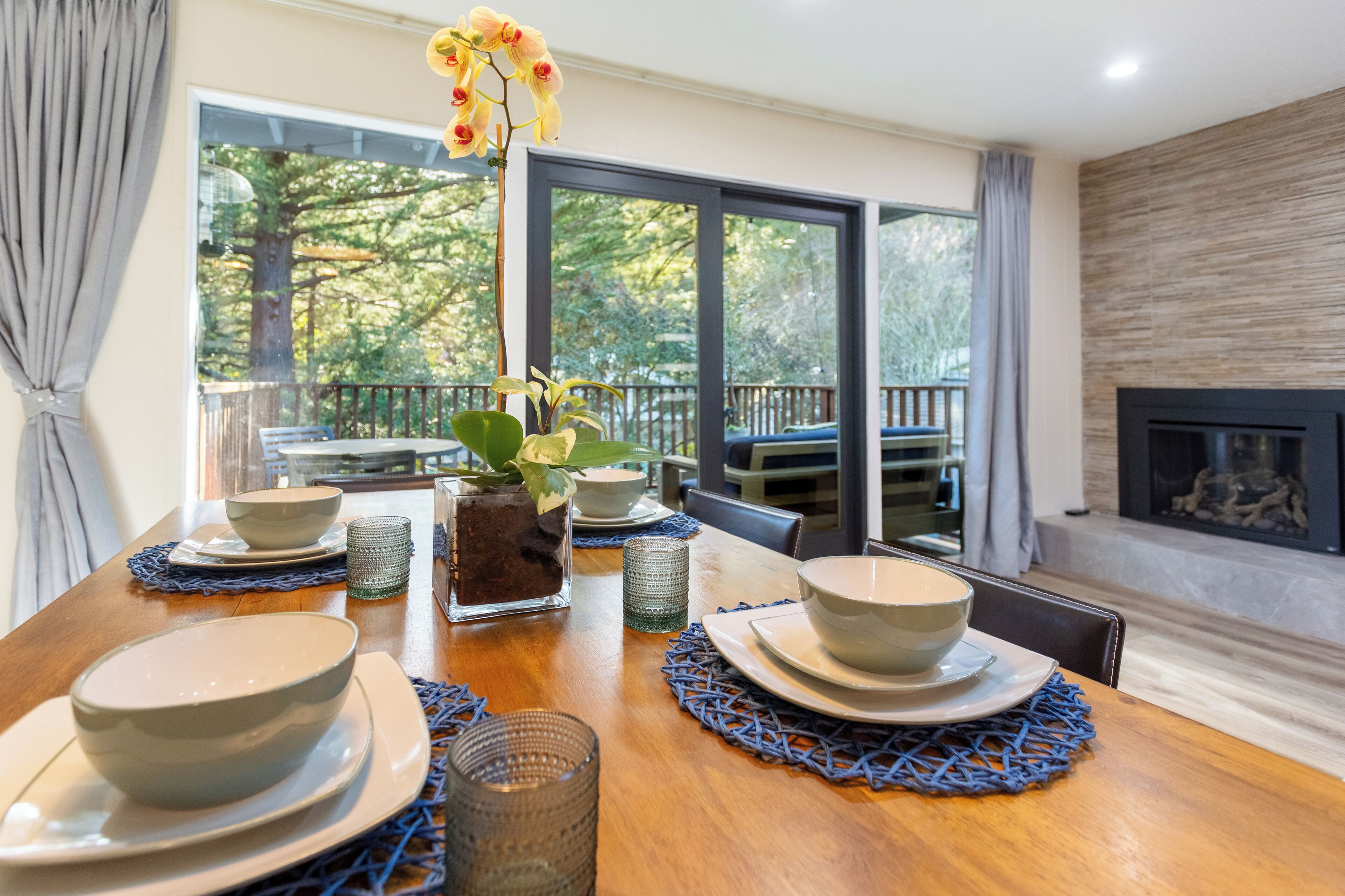 A dining table set with bowls, glasses, and a vase with flowers.