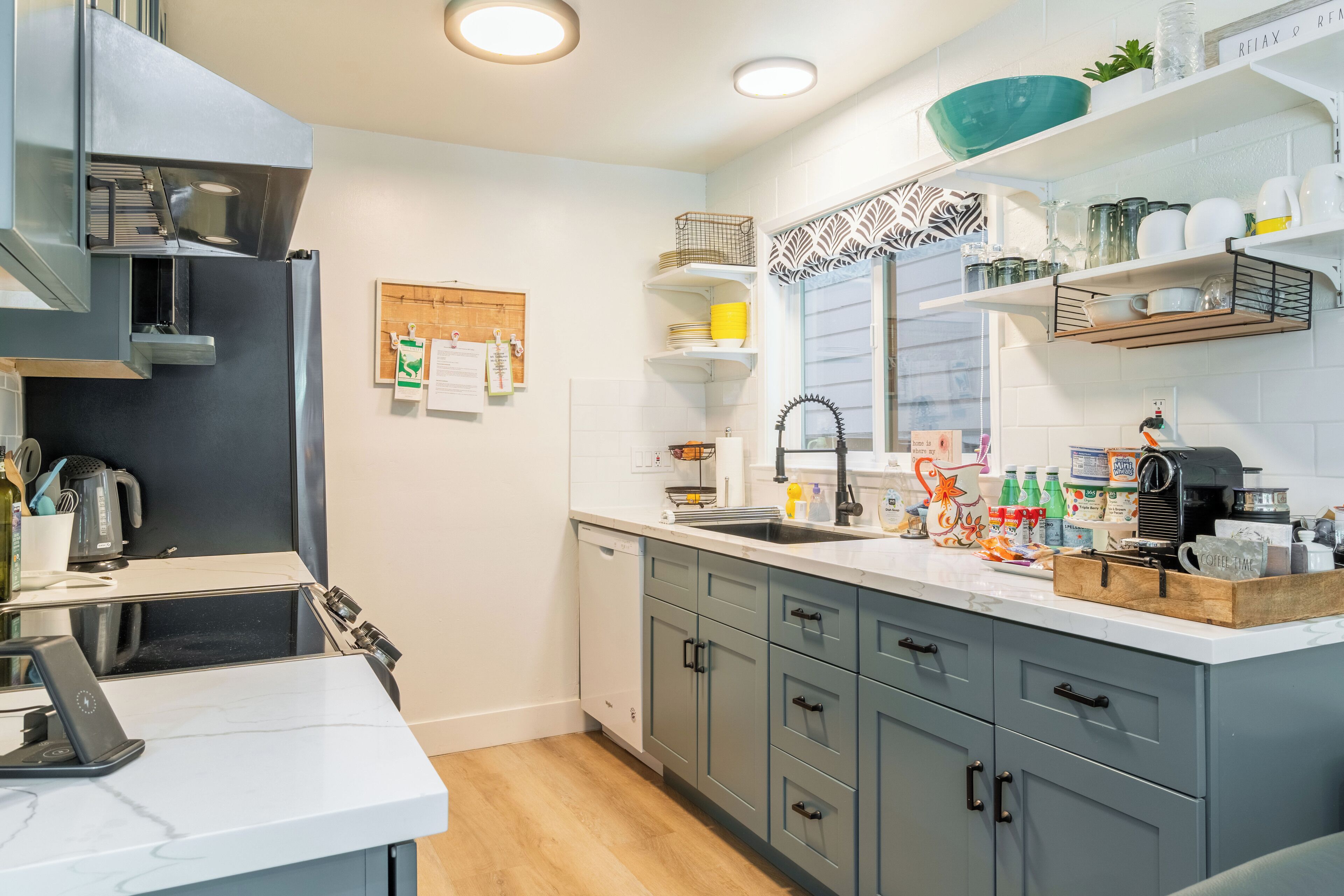Una cucina moderna con mobili grigi, un piano di lavoro bianco e diversi elettrodomestici.