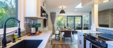 A modern kitchen with a large window, a dining area, and a built-in oven.