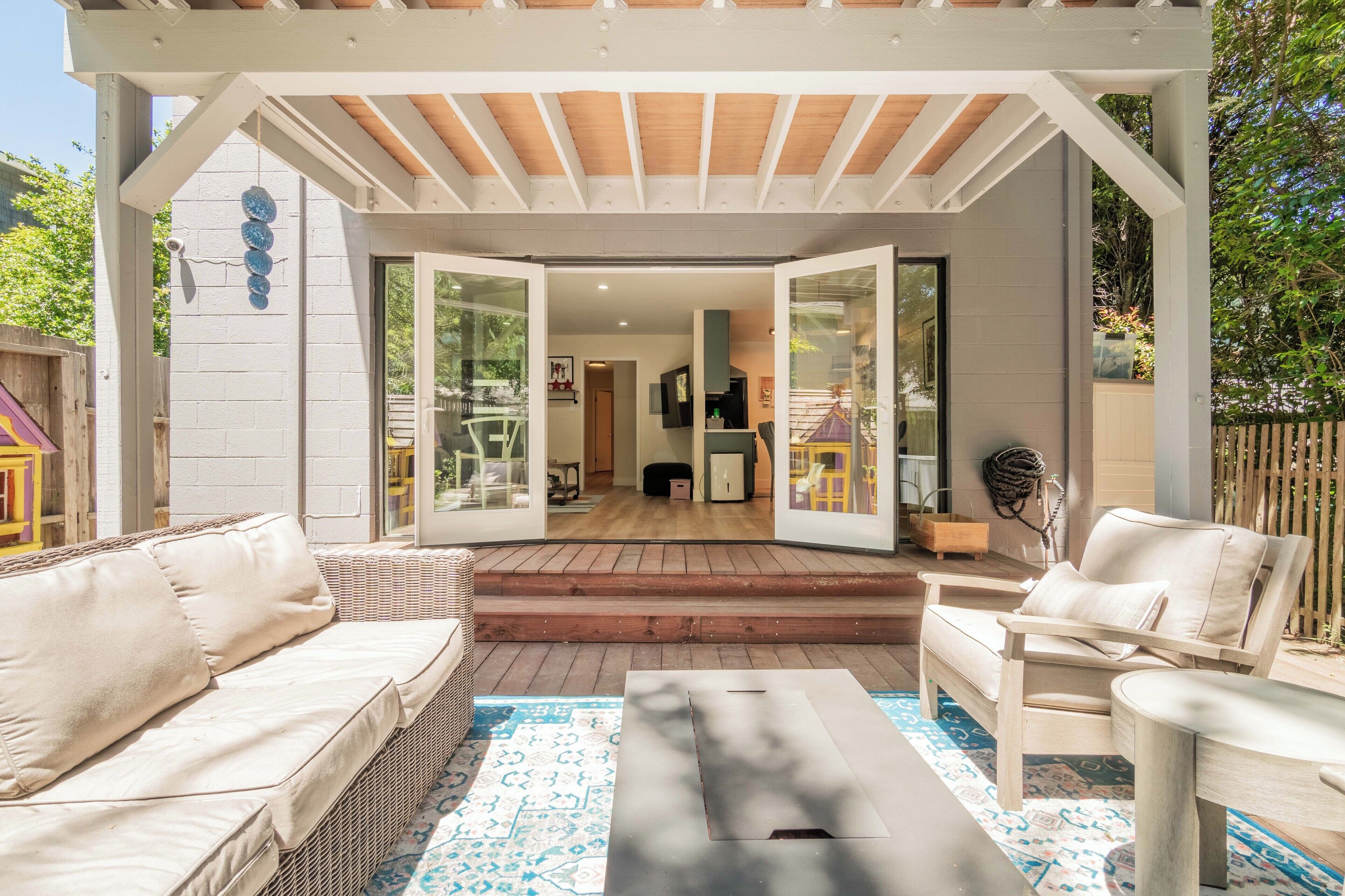 An open patio with a covered seating area, a wooden deck, and a view into the house.