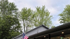 A building with a covered porch, an American flag, and outdoor seating. - Quiet 3-bedroom home on 4 aces near Lake Sullivan (Sullivan)