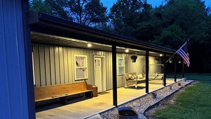 A covered outdoor seating area with benches, a small trash can, and an American flag. - Quiet 3-bedroom home on 4 aces near Lake Sullivan (Sullivan)