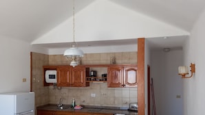 Una cocina compacta con armarios de madera, lavadora, mesa de comedor con sillas y una lámpara colgante.