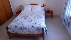 Un dormitorio con una cama de madera, dos mesitas de noche y un tocador con una lámpara.