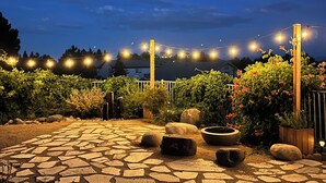 An outdoor patio area with stone flooring, potted plants, and string lights.