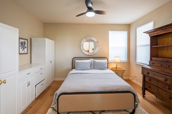 A bedroom with a bed, a ceiling fan, a round mirror, a dresser, and a window. - Modern Mountain Retreat
Hot tub, Sauna and outdoor firepit (Reno)