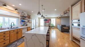 A modern kitchen with wooden cabinets, a marble island, and pendant lighting.