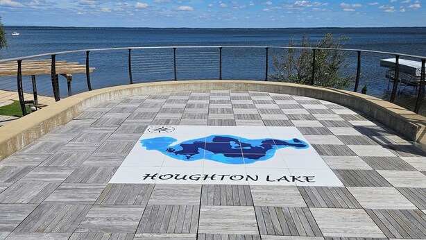 Un muelle de madera con un cartel que dice "Houghton Lake" y vista al lago.