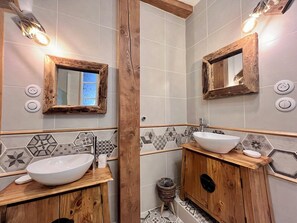 A bathroom with a wooden vanity, a white sink, and a mirror with a rustic frame.
