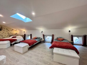 A room with three beds, a skylight, and a stone wall.
