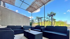 Un espace extérieur aménagé avec des meubles en osier et un sol carrelé.