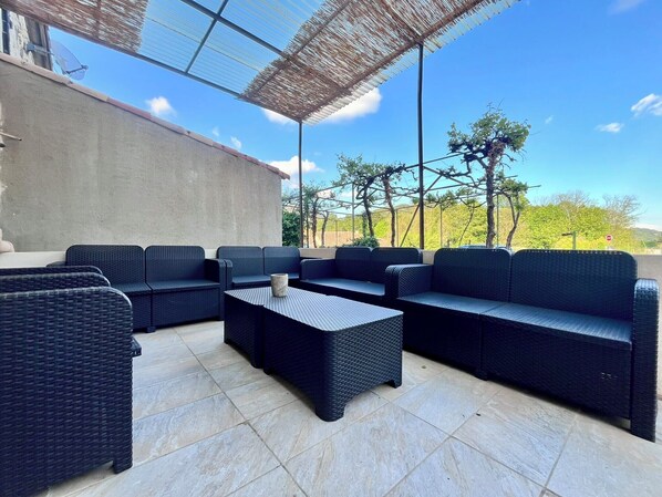 An outdoor seating area with wicker furniture and a tiled floor.