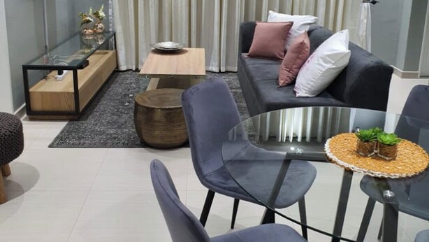 Una sala de estar moderna con un sofá, sillones, una mesita de centro, un televisor y una cortina.