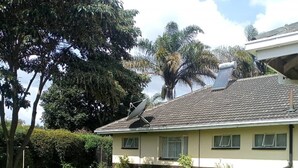 Een huis met twee verdiepingen, een pannendak, een schotelantenne en een verzorgd gazon.