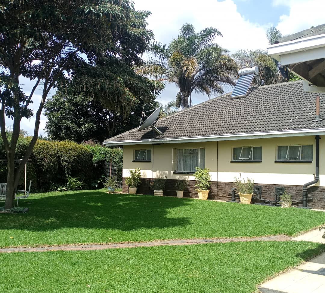 A two-story house with a tiled roof, a satellite dish, and a well-maintained lawn.