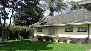 A two-story house with a tiled roof, a satellite dish, and a well-maintained lawn.