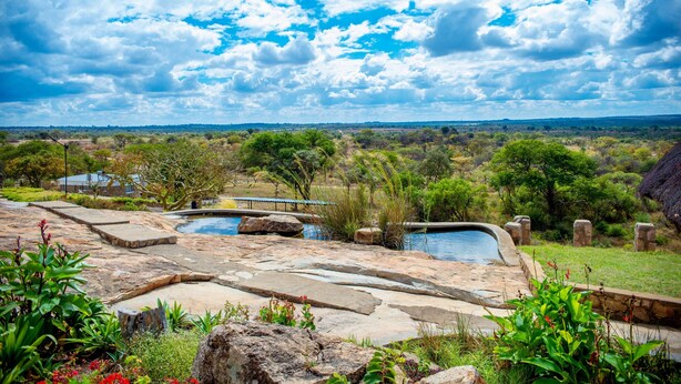 Zona de piscina con escalones de piedra y vistas a un paisaje natural.