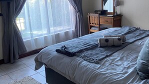 A bedroom with a bed, a dresser, a mirror, and a television.