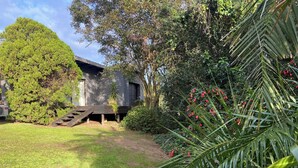A residential property with a well-maintained lawn, a wooden deck, and a large tree providing shade.