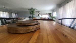 A dining area with a wooden table, chairs, and a view of the living room.