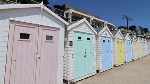 A row of colorful beach huts with a balcony and a clock. - Cedar 1 (Axminster)