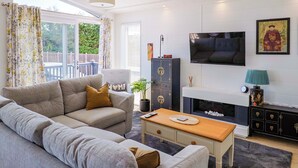 A modern living room with a sofa, a coffee table, a TV, and a fireplace. - Cedar 1 (Axminster)