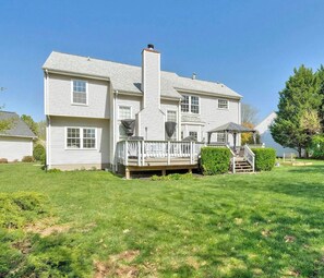 A two-story house with a front deck, a chimney, and a covered porch.