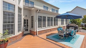 Une maison dotée d’un patio couvert comprenant une table et des chaises, un grand parasol et des fondations en briques.